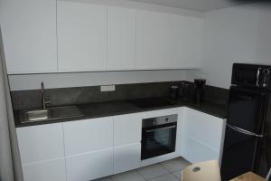 a kitchen with white cabinets and a black refrigerator at SeaSide4you in De Haan