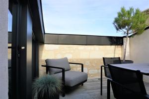 eine Terrasse mit einem Stuhl, einem Tisch und einem Baum in der Unterkunft Hôtel Cardinal Bordeaux Centre in Bordeaux