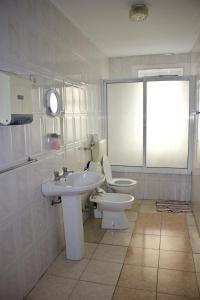 uma casa de banho com um lavatório, um WC e uma janela. em Residencial Rivoli no Fundão