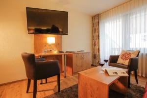 a living room with a couch and a desk with a television at Landhotel Goldener Stern in Trautskirchen