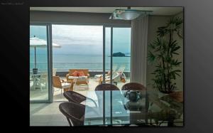 a dining room with a glass table and a view of the ocean at Cobertura Praia de Palmas in Governador Celso Ramos