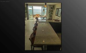 a kitchen with a long table with chairs and the ocean at Cobertura Praia de Palmas in Governador Celso Ramos
