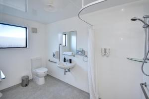 a white bathroom with a toilet and a sink at ASURE Adrian Motel in Dunedin