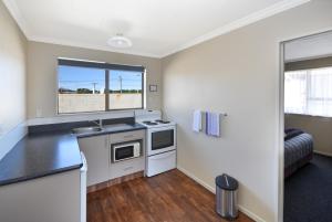 a kitchen with a stove and a sink and a window at ASURE Adrian Motel in Dunedin