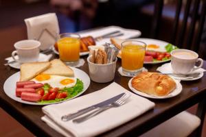 una mesa con platos de desayuno y tazas de zumo de naranja en Na Dvoryanskoy Hotel, en Samara