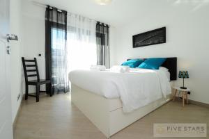 ein weißes Schlafzimmer mit einem großen weißen Bett und einem Stuhl in der Unterkunft Suite Relax Five Stars Holiday House in Nizza