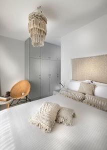 a white bedroom with a bed with pillows and a chandelier at Simousi Villas in Kithnos