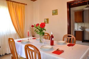 una mesa con un jarrón de rosas rojas. en Villa Eleni Peritheia BY CorfuEscapes, en Agios Spiridon, Corfú