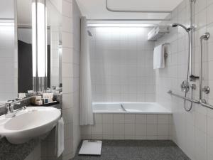 a white bathroom with a sink and a bath tub at Crowne Plaza Auckland, an IHG Hotel in Auckland