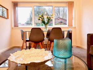 a dining room table with chairs and a vase of flowers at South Calder House in Wishaw