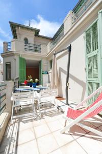 een patio met een tafel en stoelen en een parasol bij La terrasse Apartment Five stars holiday house in Nice