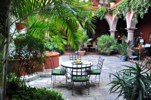 una mesa y sillas en un patio con plantas en Casa de la Cuesta B&B en San Miguel de Allende