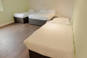 - 2 lits dans une petite chambre dotée de parquet dans l'établissement Primelodge Doncaster, à Doncaster