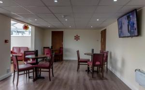 a waiting room with tables and chairs and a tv at Primelodge Doncaster in Doncaster