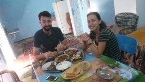 a man and woman sitting at a table with a plate of food at Shater Nubian House in Aswan