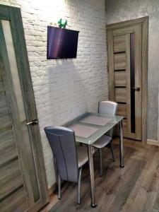 a table with two chairs and a television on a wall at Apartment "Comfort" in the Center in Chernivtsi