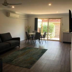 a living room with a couch and a table and chairs at Tic Tac Toe Quality Accommodation in Armidale