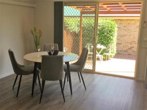 a dining room with a glass table and chairs at Tic Tac Toe Quality Accommodation in Armidale