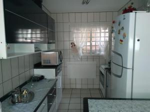 cocina con nevera blanca y fregadero en Condomínio Vila Paradiso, en Serra Negra