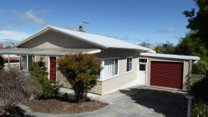 una pequeña casa blanca con garaje rojo en Position on Alexander, en Bridport