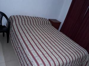 una cama con una manta a rayas encima en Bungalow Anita Nº4 en Colón