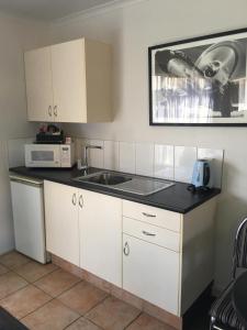 a kitchen with white cabinets and a sink and a microwave at Deco City Motor Lodge in Napier