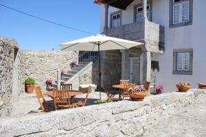 un patio con mesa, sillas y sombrilla en Casa do Nato -Turismo Rural, en Viana do Castelo