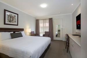 um quarto de hotel com uma cama grande e uma secretária em Elm Tree Motel em Warrnambool