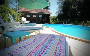a pool with two chairs and a table and an umbrella at La Coterie Lodges in Blaudeix +8 photos