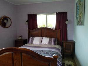 um quarto com uma cama de madeira e uma janela em Ironsands B&B em Patea
