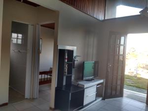 a living room with a television and a door to a room at cantinho do yuji in Cabo Frio