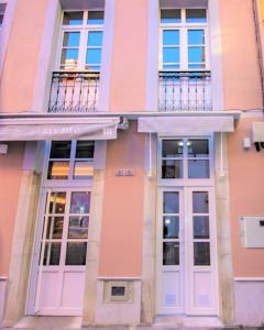 プラビアにあるApartamentos Siloの白いドアと窓のあるピンク色の建物