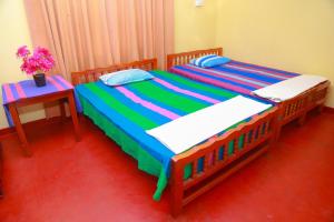 due letti in una camera da letto con un tavolo e dei fiori di Lucullus Garden a Bentota