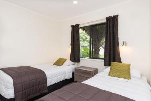 A bed or beds in a room at Kauri Park Motel