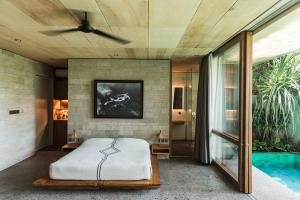 a bedroom with a bed and a ceiling fan at The Slow in Canggu