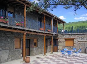 a building with a table and chairs on a patio at Albergue El Solitario in Baños de Montemayor