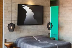 a bedroom with a bed and a tv on a brick wall at The Slow in Canggu