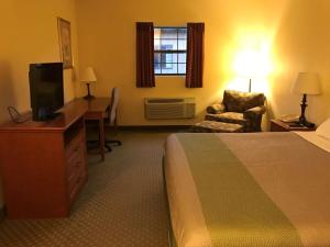 een hotelkamer met een bed, een televisie en een stoel bij Motel 6-Bloomsburg, PA in Bloomsburg