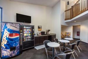 uma cafetaria com mesas e cadeiras e uma máquina de refrigerantes em Motel 6-Saukville, WI em Saukville