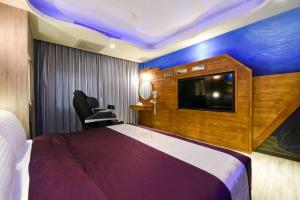 a hotel room with a large bed and a flat screen tv at Meng Siang Motel in Pingzhen