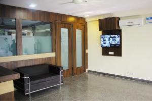 a waiting room with a black couch and a tv at SKS Hospitality in Gurgaon