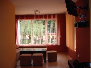 Sala de estar con ventana, mesa y taburetes en Villa Nanevi, en Teteven