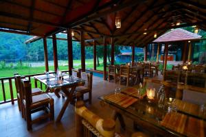 a restaurant with wooden tables and chairs in a field at Vayal Veedu - Luxury Farm Villas by the woods in Muthanga