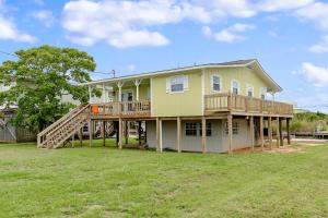 une grande maison avec une terrasse et une cour dans l'établissement Canal Cottage, à Dauphin Island