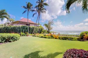 une pelouse devant une maison avec des palmiers et l'océan dans l'établissement Lanikai Condos, à Kapaa