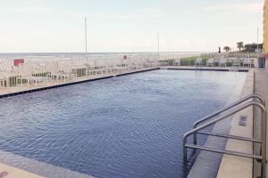 a swimming pool at a resort with a beach at Oceania Plaza & Suites in New Smyrna Beach