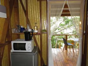 a kitchen with a microwave on top of a refrigerator at la Cabane de la Vallee in Dumbéa