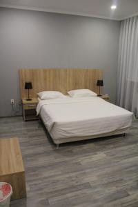 a bedroom with a large white bed and two tables at Hotel Inju Hills in Astana