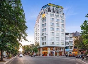 un edificio blanco con un cartel en la parte superior en Nesta Hotel Hanoi, en Hanói