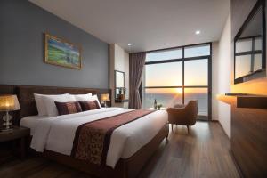a bedroom with a large bed and a large window at Nolis Hotel in Vung Tau